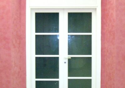 Porta vetrata laccata bianco a due ante con scatola di ventilazione, opera della Falegnameria Rangoni Basilio per La Fabbrica del comune di Scandicci.